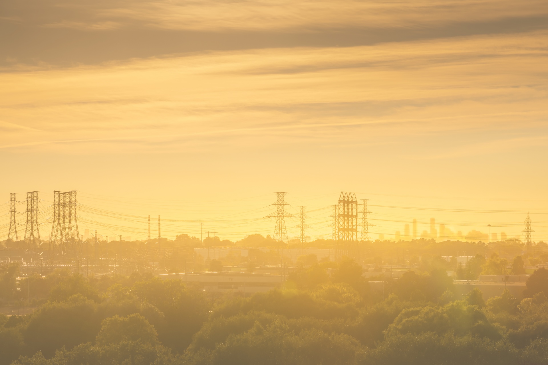 Power transmission lines silhouetted against a glowing sunset sky